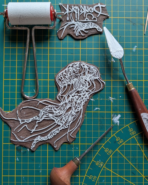 Plaque de lino gravée et encrée, ici le motif méduse ainsi que le "logo Doukypick" pour la réalisation d'une impression blanche sur T-shirt noir. 