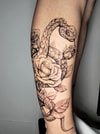 Tatouage d'un serpent s'enroulant autour de roses sur le mollet